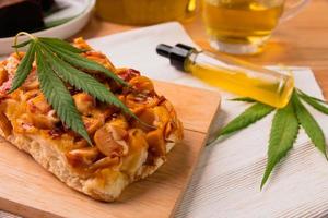 Homemade pizza with marijuana or cannabis leaf on wooden tray. photo