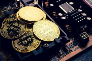 Golden coins with bitcoin symbol on a mainboard. photo