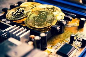 Golden coins with bitcoin symbol on a mainboard. photo