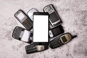 Many obsoleted cellphones and a smartphone on a grunge background. photo