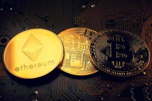 monedas de oro con símbolo de ethereum y bitcoin en una placa base. foto