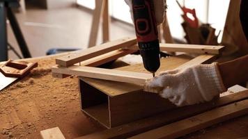 carpintero usando taladro para atornillar piezas de tablero en el sitio.