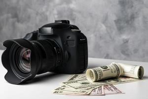 A black digital camera and banknotes on a white table with grunge background. photo