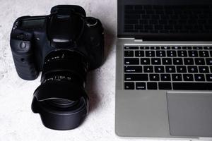 A black digital camera and a computer laptop on a table. photo