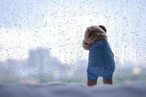 oso de peluche llorando en la ventana en un día lluvioso. foto