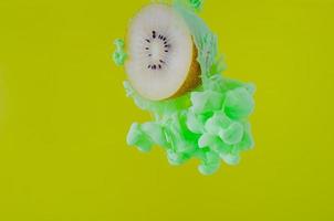 Slice kiwi fruit with partial focus of dissolving green poster color photo