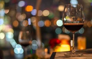 A glass of red wine on table of rooftop bar. photo