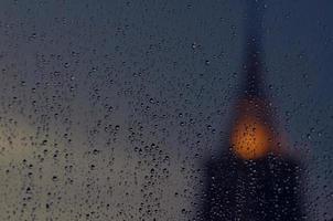 Partial focus of rain drop on glass window in monsoon season with blurred  pagoda of temple  background. photo