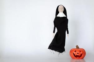 Scary nun ghost that no mouth with pumpkin on the floor.  Halloween minimal concept. photo
