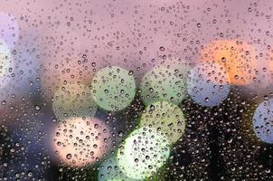 Rain drop on glass window in monsoon season with colorful bokeh light