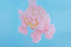 Slice lemon with partial focus of dissolving pink poster color in water photo