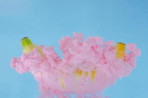A banana fruit with partial focus of dissolving pink poster color in water photo
