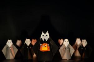 el origami de halloween o la monja plegable de papel sosteniendo la cabeza de calabaza jack o linterna hecha de papel doblado con muchas monjas en el fondo. foto