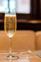 A glass of Champagne puts on marble table in restaurant for celebration with blurred background. photo