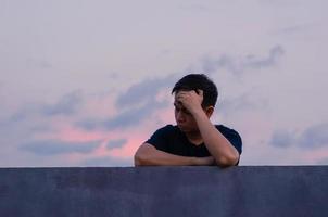 Asian miserable depressed man stay alone with sky background. Depression and mental health concept.