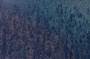 Focus and blurred photo of Rain drop on glass window with dark blue color and light reflection on it for abstract and background concept.