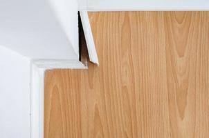 Breaking white skirting board at the corner on parquet or wooden floor. photo