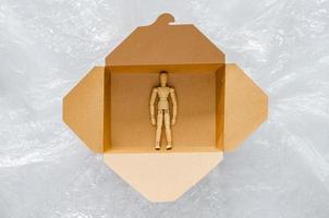 Wooden model stay safe inside disposable, compostable paper food box that surrounding with plastic bag. World environment day concept. photo