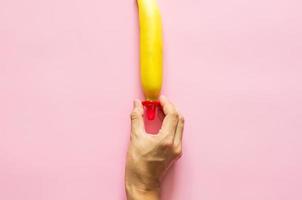 Hand holding condom to put in banana for minimal safe sex, world sexual health and aids day concept. photo