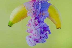 A banana fruit with partial focus of dissolving pink and purple poster color photo