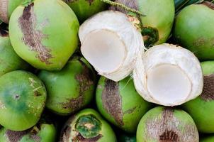 jóvenes frutas de coco tailandesas dulces frescas puestas en sus hojas verdes para el concepto de fruta de verano. foto