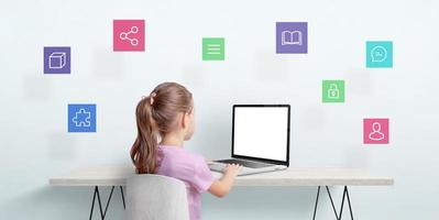 Little girl work on a laptop computer. Internet of things concept. Isolated laptop display for mockup. Icons are floating above the table photo