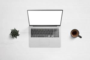 Laptop on work desk with isolated screen for app or web page design showcase. Top view, flat lay composition with plant and coffee mug beside photo