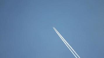 straalvliegtuig dat hoog in de lucht vliegt, laat contrails achter in de heldere blauwe lucht. video