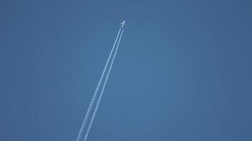 avião a jato voando alto no céu deixando rastros no céu azul claro. video