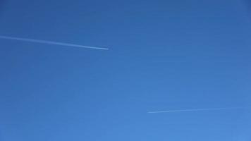 twee straalvliegtuigen die hoog in de lucht naar elkaar vliegen en contrails achterlaten in de heldere blauwe lucht. video