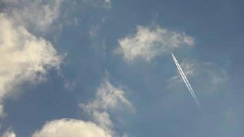 Jet airliner flying high in the sky leaves contrails in the clear blue sky. video