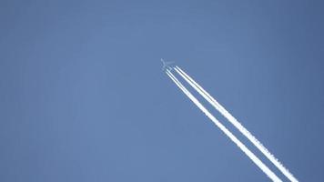 Düsenflugzeug, das hoch in den Himmel fliegt, hinterlässt Kondensstreifen am klaren blauen Himmel. video