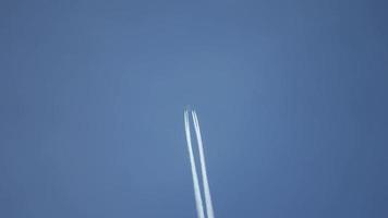 Jet airliner flying high in the sky leaves contrails in the clear blue sky. video