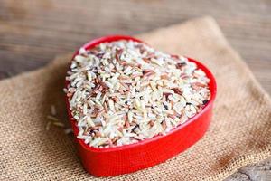 heart rice , brown rice on the sack , various color mixed thai rice for cooking food , Loonzain rice brown black red white purple health food background. photo