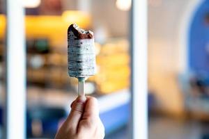 mano sosteniendo palitos de helado de chocolate verde con fondo desenfocado foto