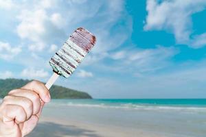 Hand holding green chocolate ice cream sticks with blur sea views and island background photo