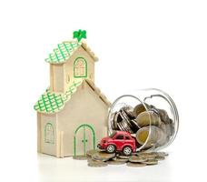 monedas en botella de vidrio y coche y casa sobre fondo blanco, ahorro empresarial y concepto de inversión foto