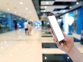 hand holding mobile smart phone with shopping mall blurred background photo