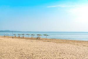 silla de playa blanca y sombrilla en una playa tropical con cielo azul foto