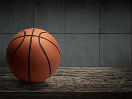 Basketball balls for sports and games are placed on a wooden table with a dark cement wall photo