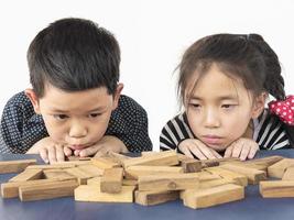 los niños juegan jenga, un juego de torre de bloques de madera para practicar su habilidad física y mental foto