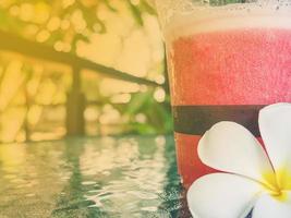 Warm vintage photo of strawberry smoothie with plumeria flower decoration in a coffee shop