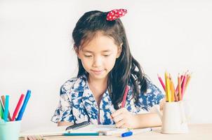 foto de estilo vintage de una niña está felizmente coloreando un libro