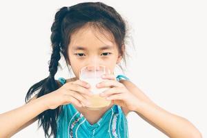 foto de estilo vintage de una chica asiática está bebiendo un vaso de leche sobre fondo blanco