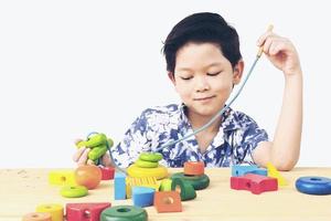 encantador niño asiático es jugar colorido juguete de bloques de madera foto