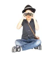 7 years old Asian traveler boy is sitting and using binoculars isolated on white background photo