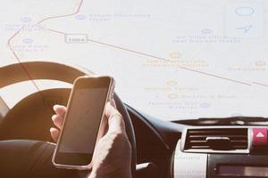 Woman is dangerously driving car while holding and looking a map navigator in her mobile phone with overlay route map photo