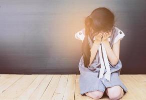 Sad Asian girl sitting on white wood floor photo