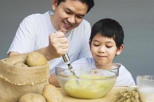 Daddy and son making mashed potatoes happily photo