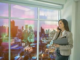 Modern business women use mobilephone talk about stock market white looking out of the window photo